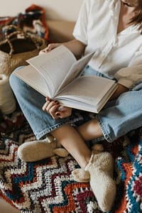 pexels-photo-5709784-5709784 Person sitting comfortably while reading, surrounded by cozy knit and crochet items.